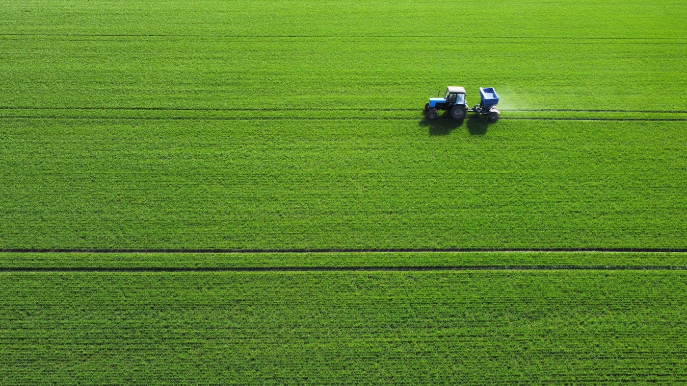 Compact tractor spraying a green field